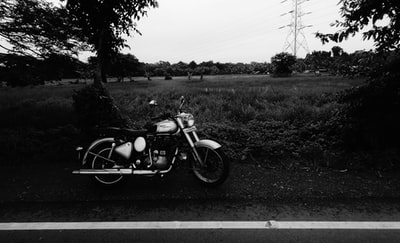 灰度摄影的摩托车停在路旁边
